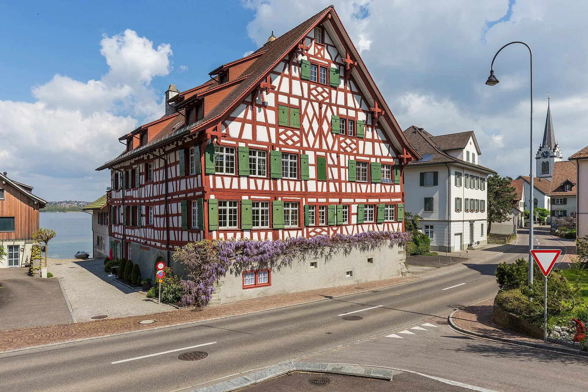 Der Kehlhof, ein rot-weisser Fachwerkbau von 1686, an der Seestrasse in Berlingen mit Kirchturm im Hintergrund