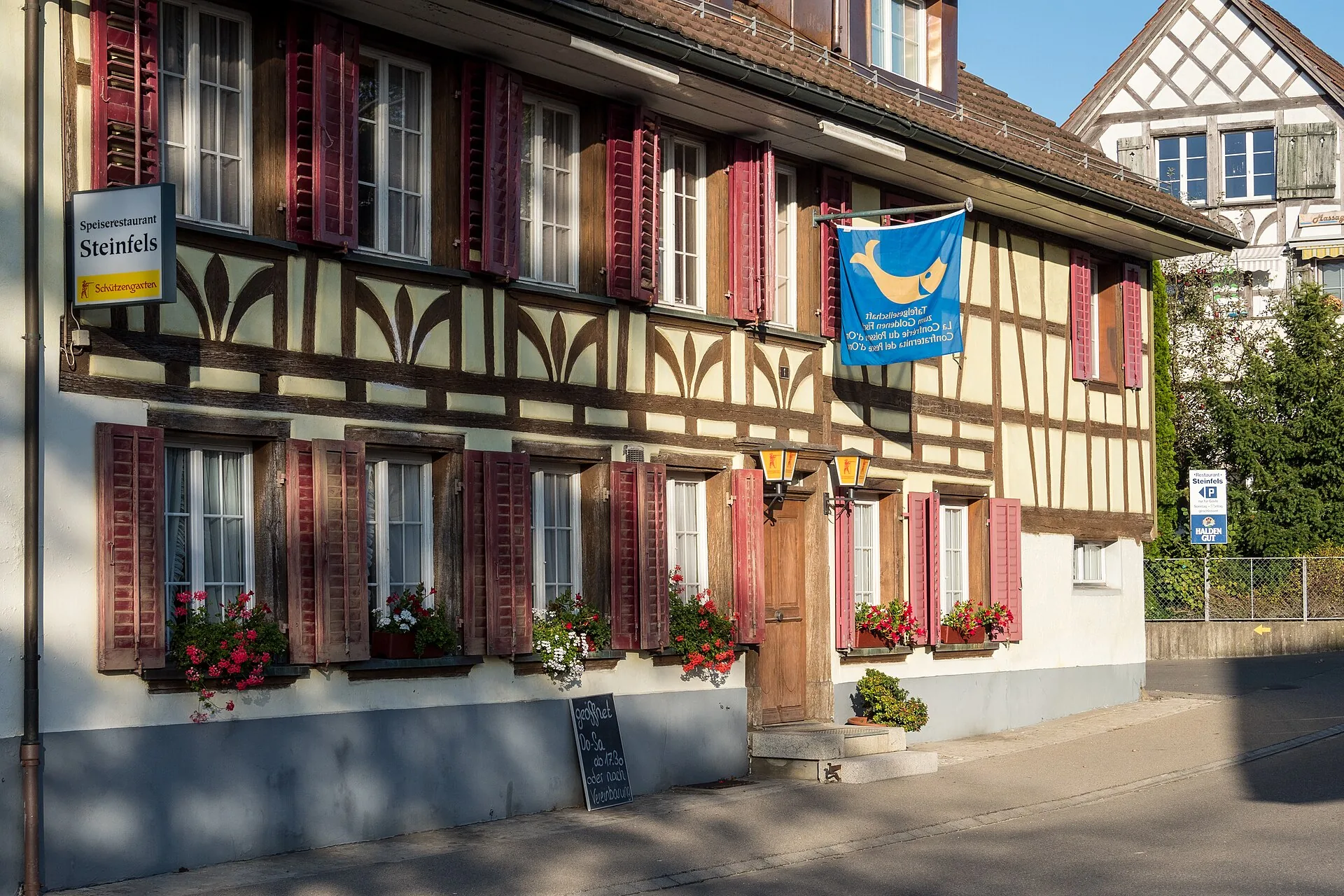 Riegelhaus des Restaurants Steinfels in Ellikon an der Thur mit roten Fensterläden und Blumenkästen