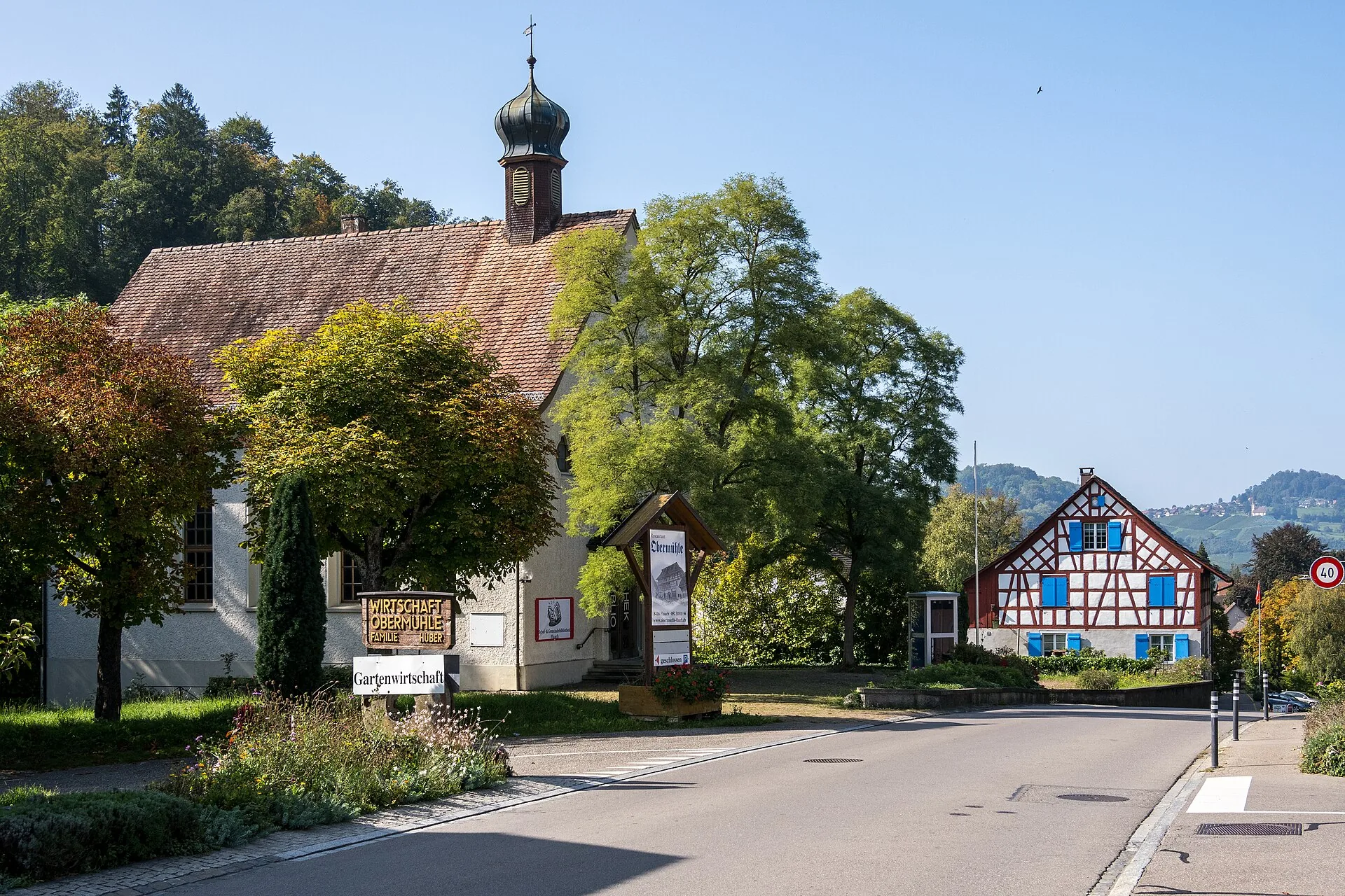 Dorfstrasse Steig in Flaach mit Kapelle mit Zwiebeltürmchen und Riegelhaus mit blauen Läden