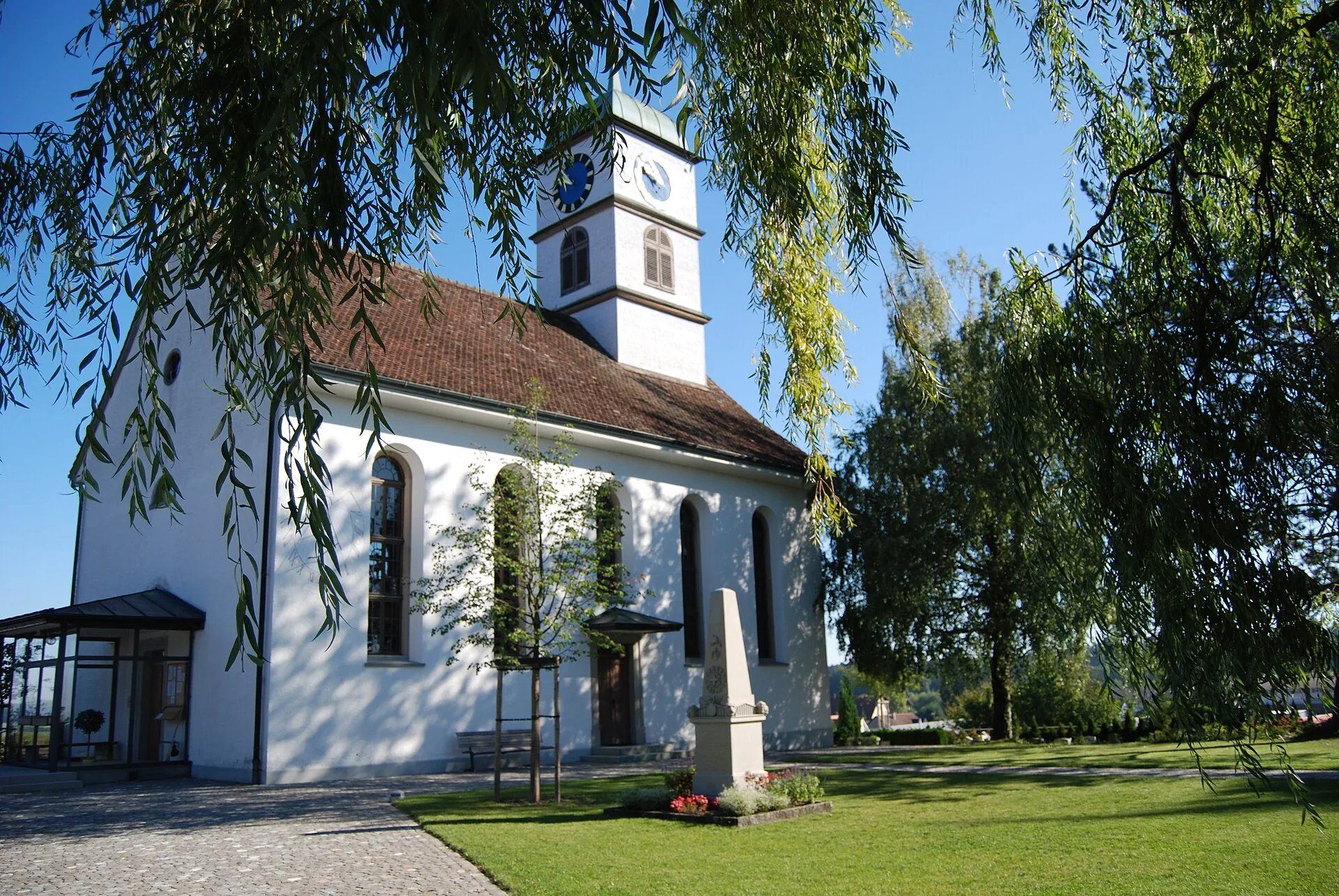 Klassizistische reformierte Kirche Henggart von 1820 mit Turmuhr und Trauerweiden