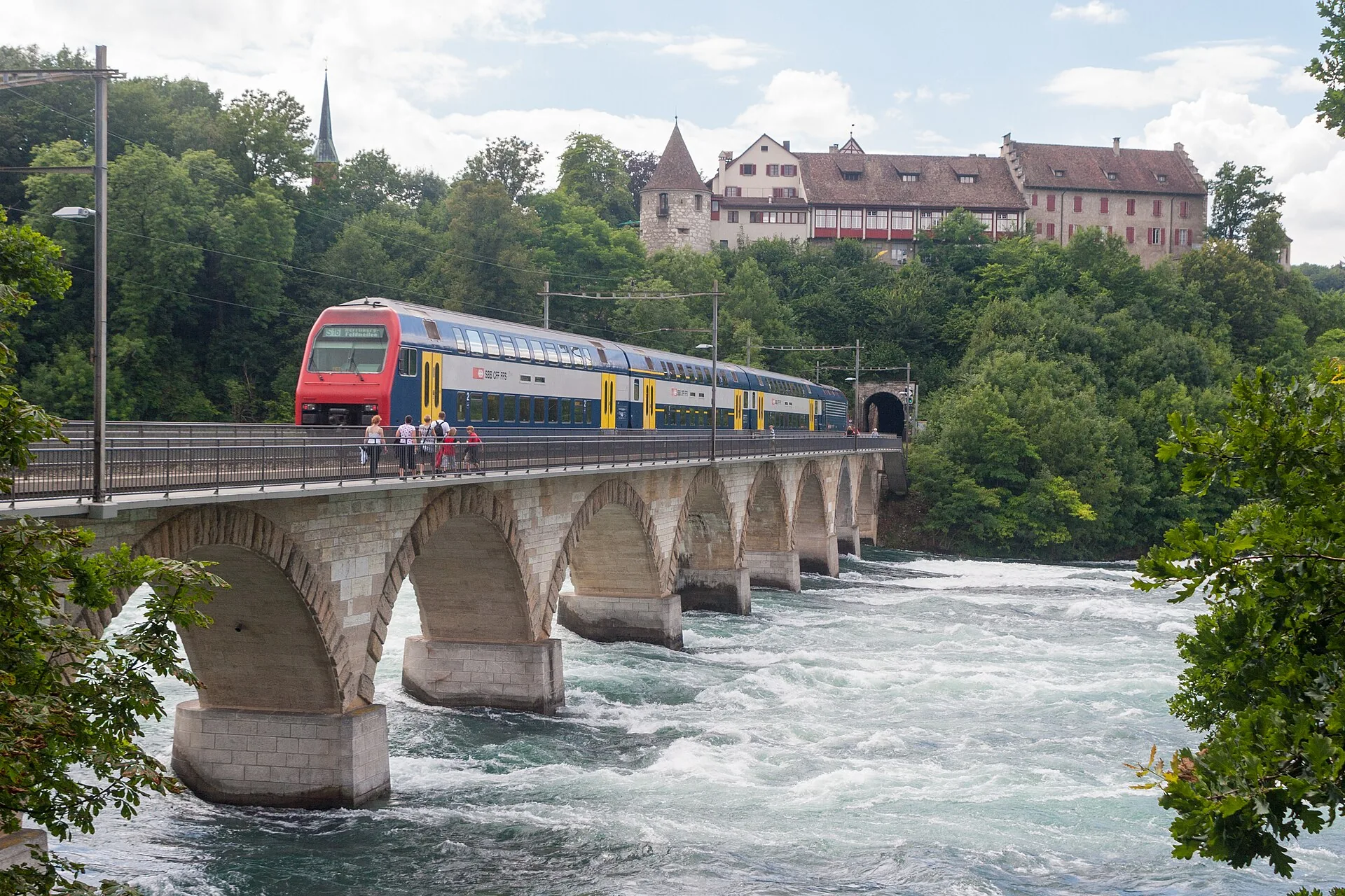 Eisenbahnbrücke über den Rhein mit S-Bahn, darüber Schloss Laufen