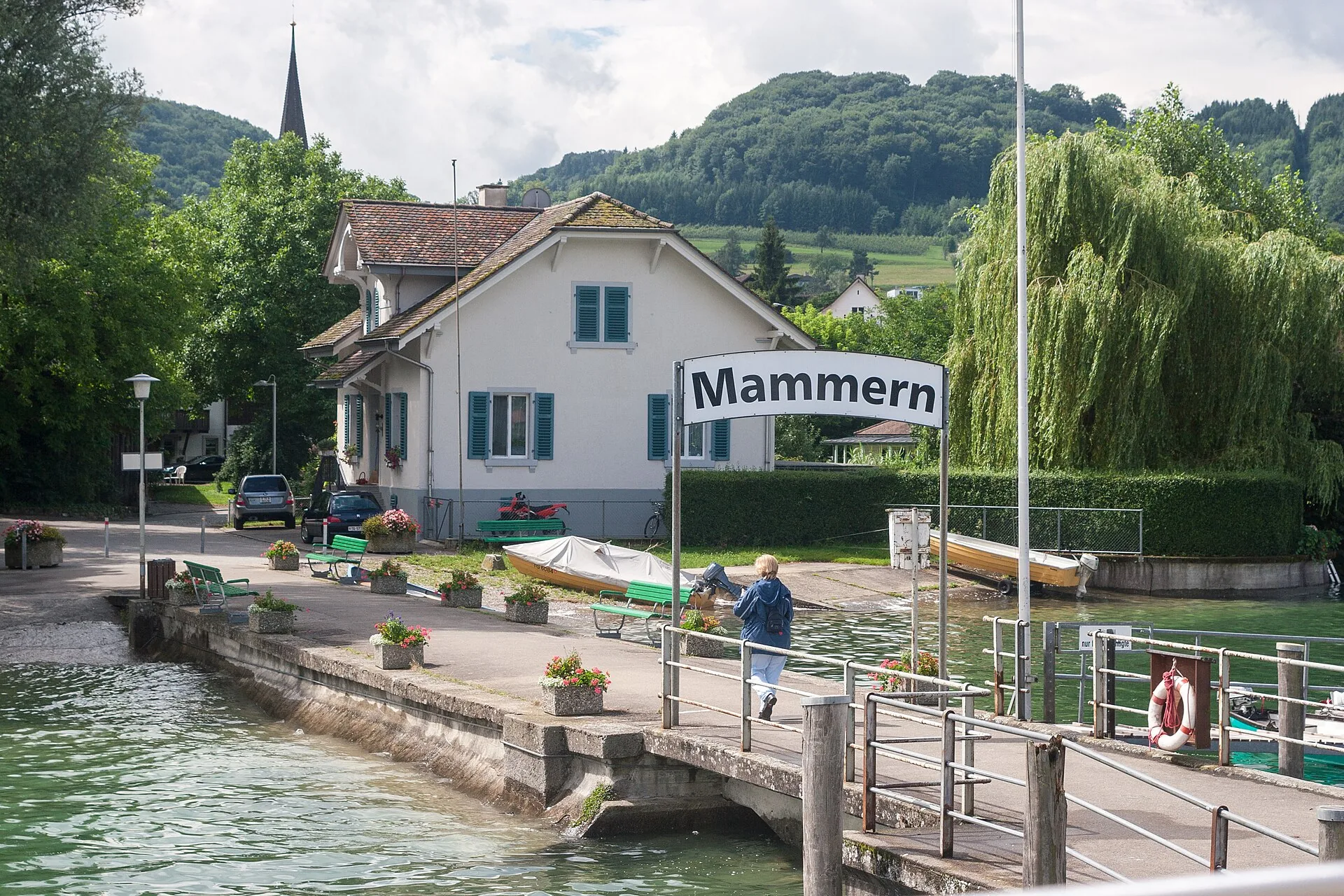 Schiffsanlegestelle Mammern mit Schild, Seeufer und Kirchturm im Hintergrund